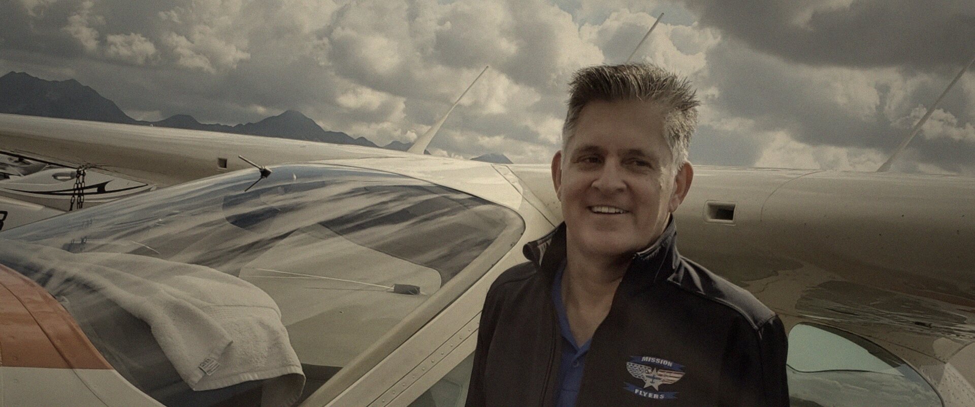 Richard beside his Cessna Cardinal under a vast sky, graded in warm first light.